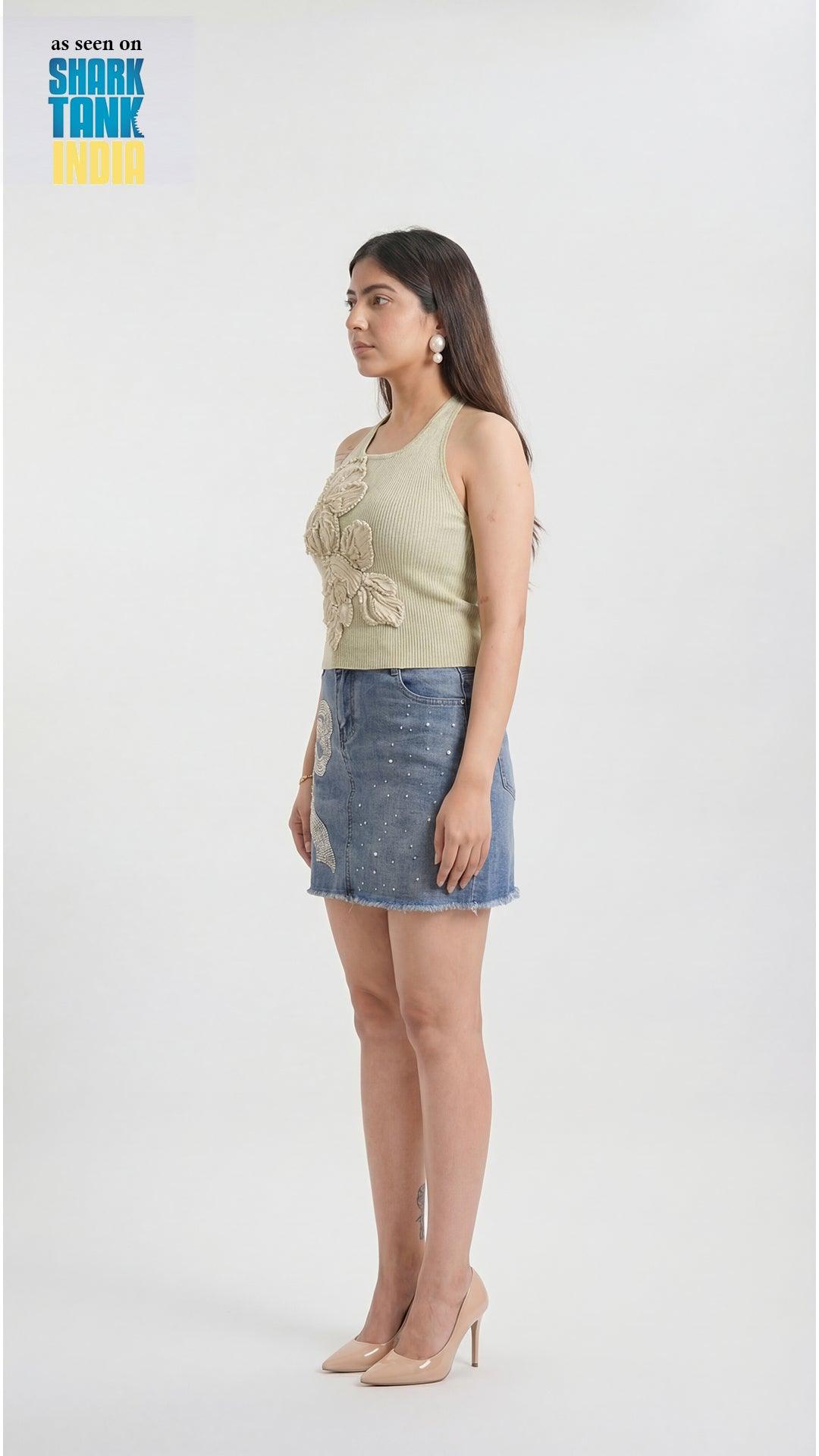 Woman wearing a light green sleeveless top and denim skirt on a white background with 'Shark Tank' branding.