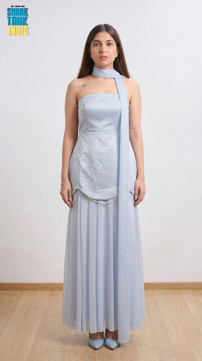 Woman wearing a light blue strapless dress with a matching shawl against a white background