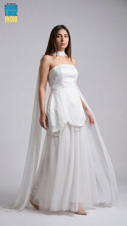 Woman wearing a white strapless gown with a sheer overlay on a gray background