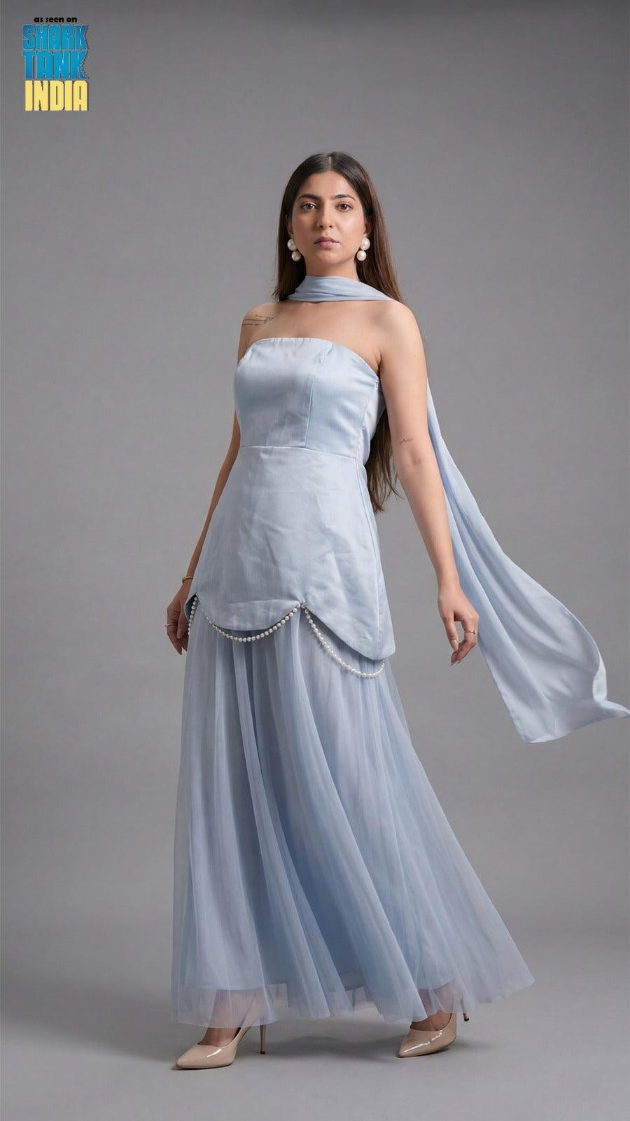 Woman wearing a light blue strapless gown with a long train on a gray background