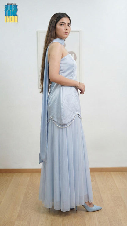 Woman wearing a light blue saree with a matching blouse in a minimal indoor setting.