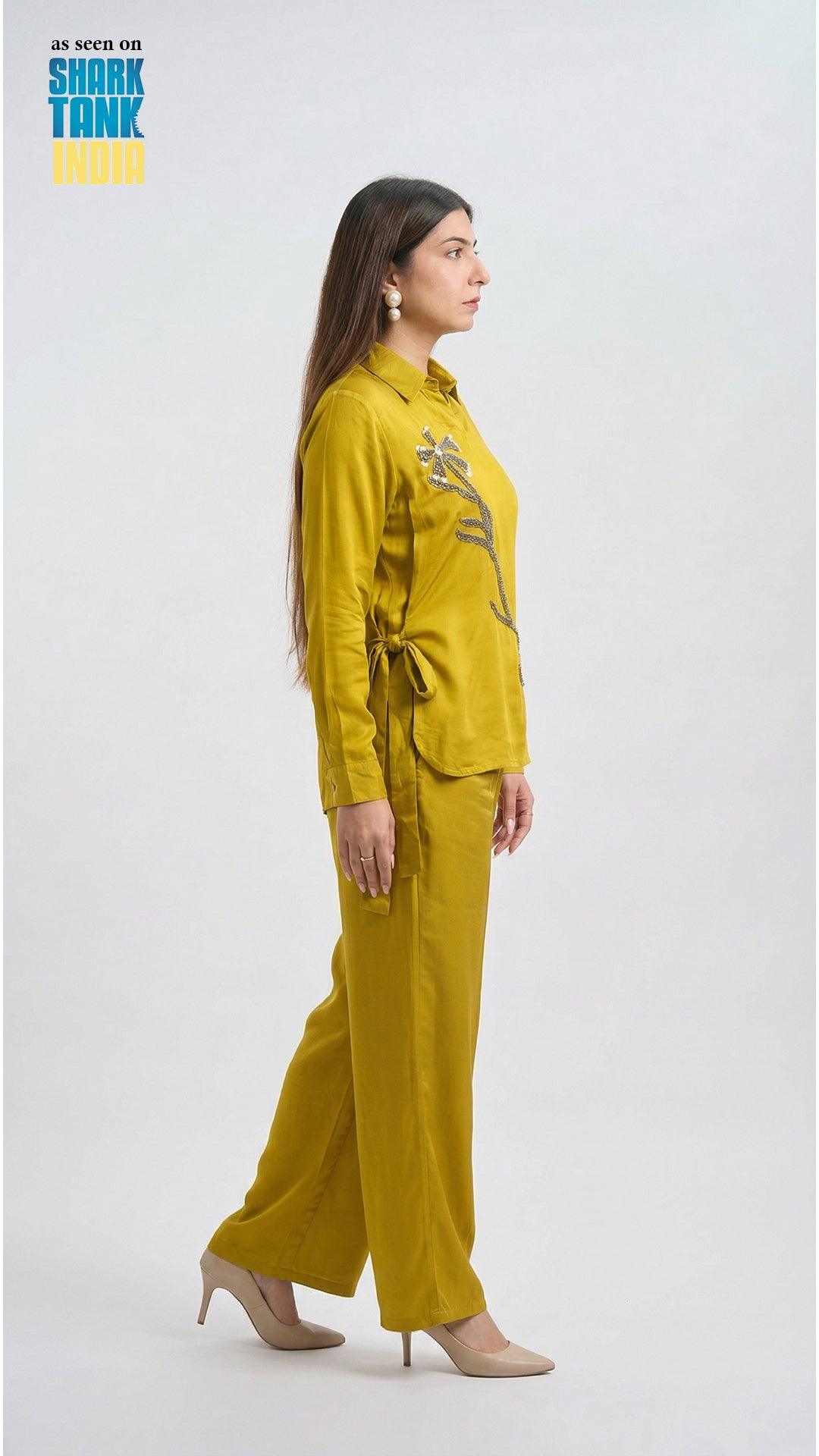 Woman wearing a mustard yellow outfit with floral design on a white background