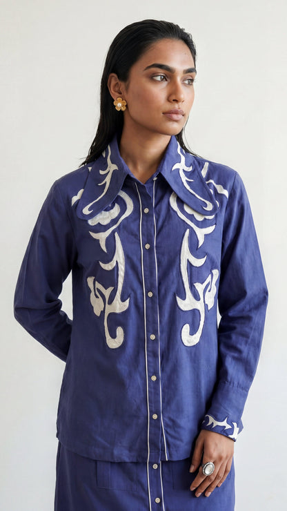 Woman wearing a blue shirt with white patterns on a plain background