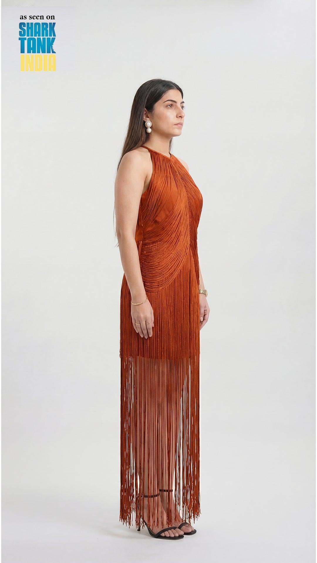 Woman wearing a rust-colored halter neck dress with fringe details on a white background, featuring Shark Tank branding.