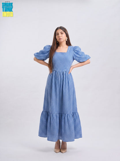 Woman wearing a blue checkered dress with puffed sleeves on a white background