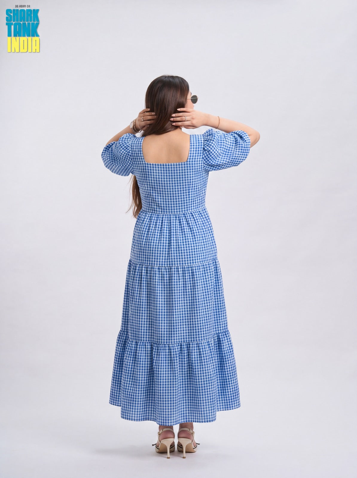 Woman wearing a blue checkered dress with a plain background
