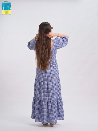Woman wearing a blue checkered dress with 'Shok Tank India' branding on a white background