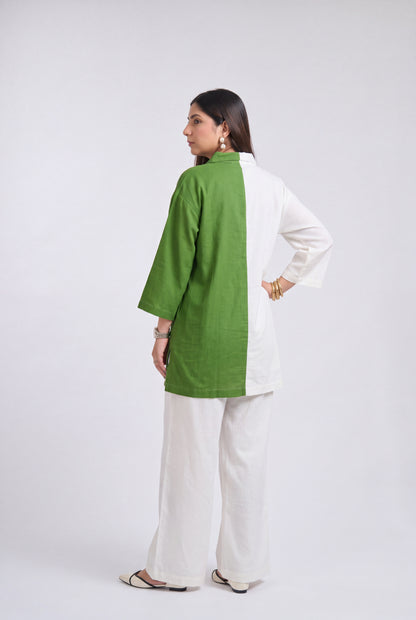 A woman modeling a two-tone green and white kurta with matching white wide-leg pants, shown from a side-back angle against a plain light gray studio background.