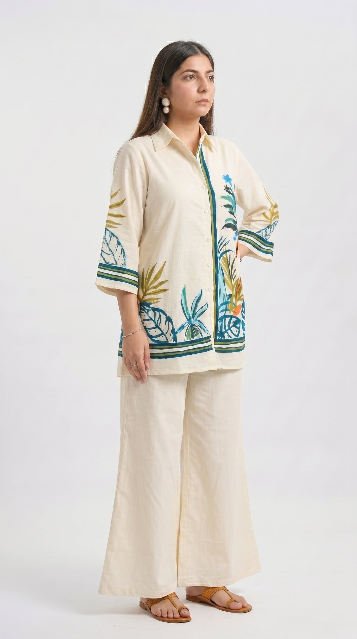 Woman wearing a cream outfit with a floral pattern on a white background