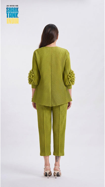 Woman wearing a green outfit with ruffled sleeves on a white background