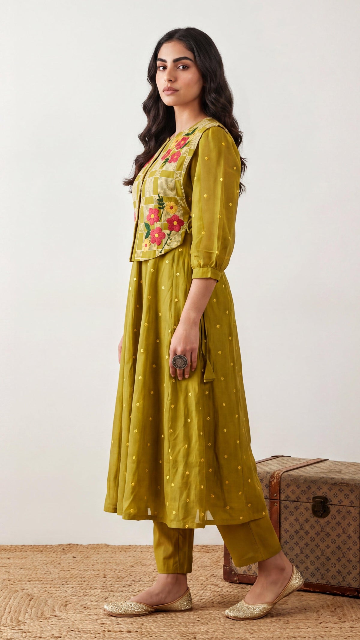 Woman wearing a mustard yellow traditional outfit with floral embroidery on a white background