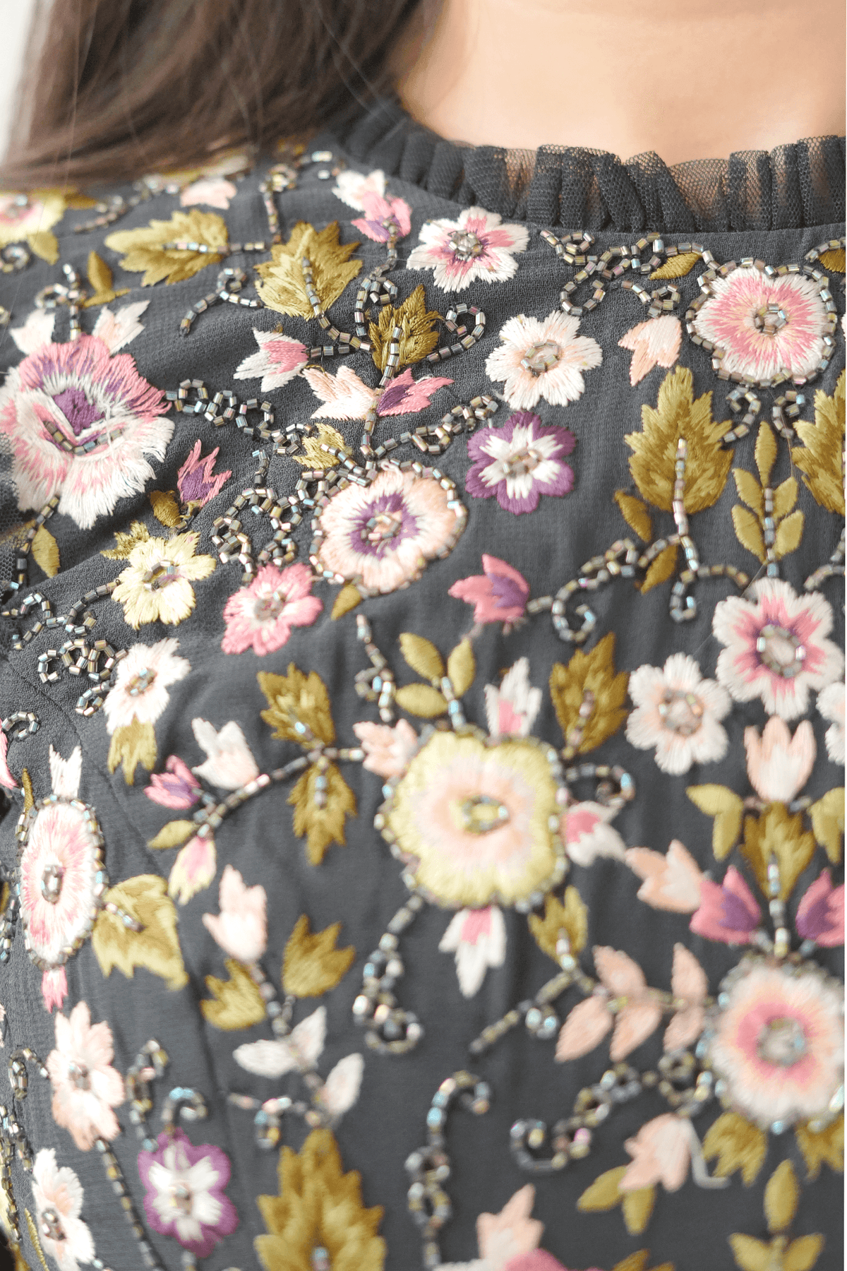 Close-up of a floral patterned fabric with pink, yellow, and green flowers on a dark background.