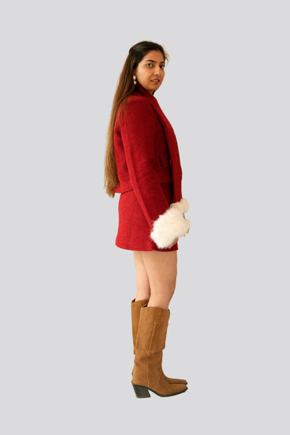 Woman wearing a red outfit with brown knee-high boots on a light gray background