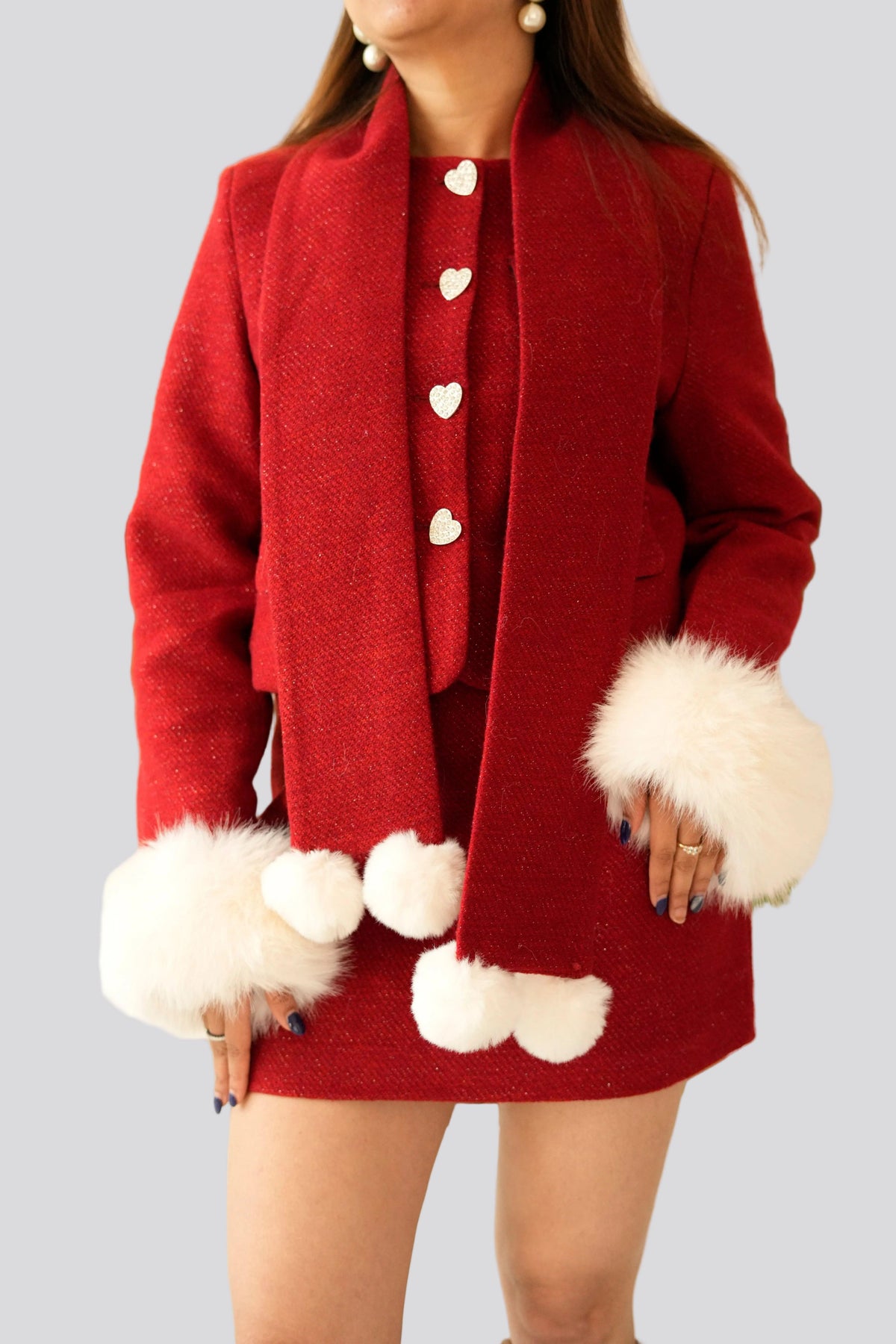 Red coat with white fur cuffs and cuffs worn by a person on a gray background