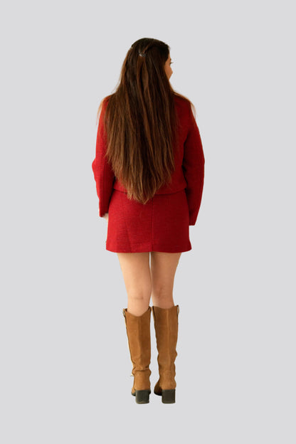 Person wearing a red outfit with brown boots on a light gray background