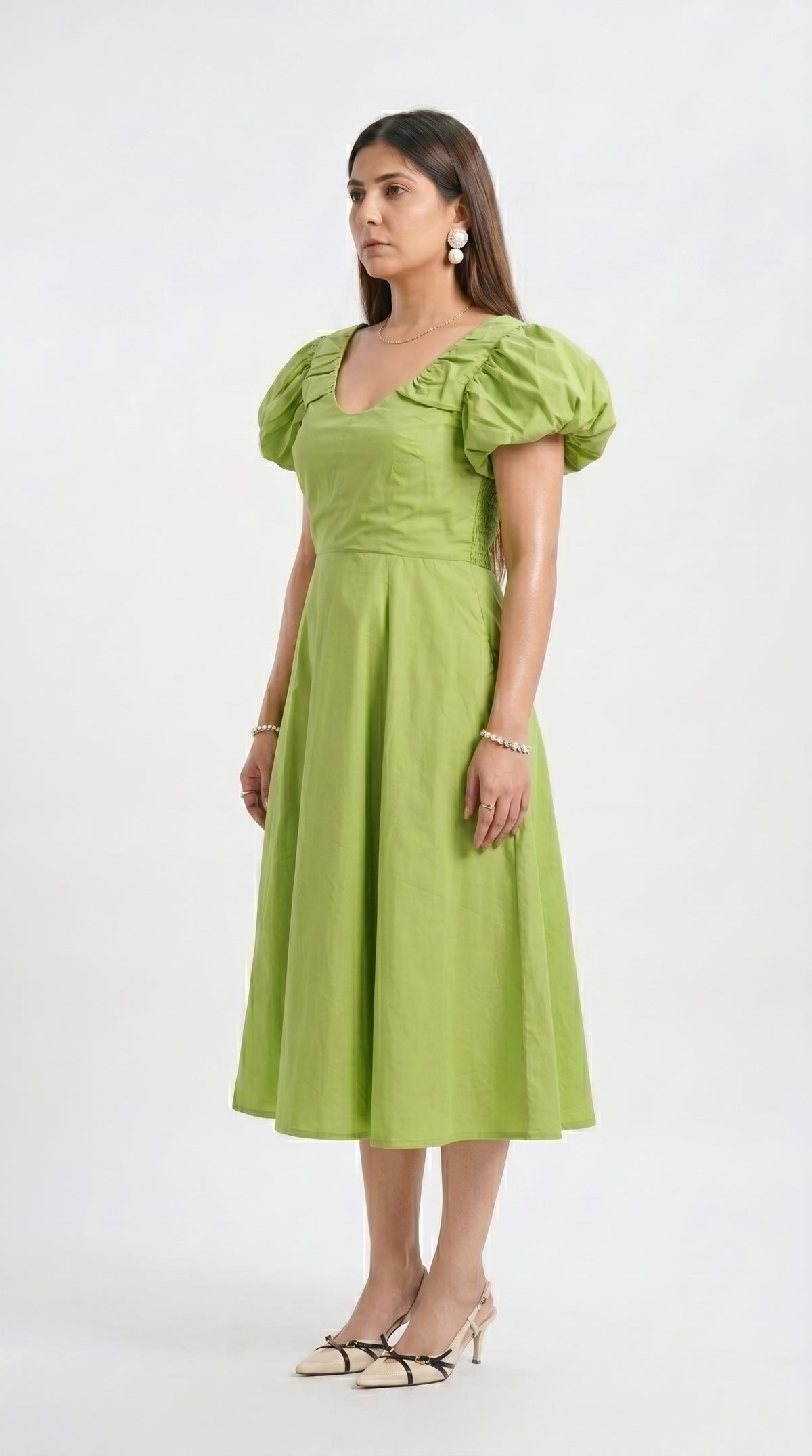 Woman wearing a green dress with puff sleeves on a white background