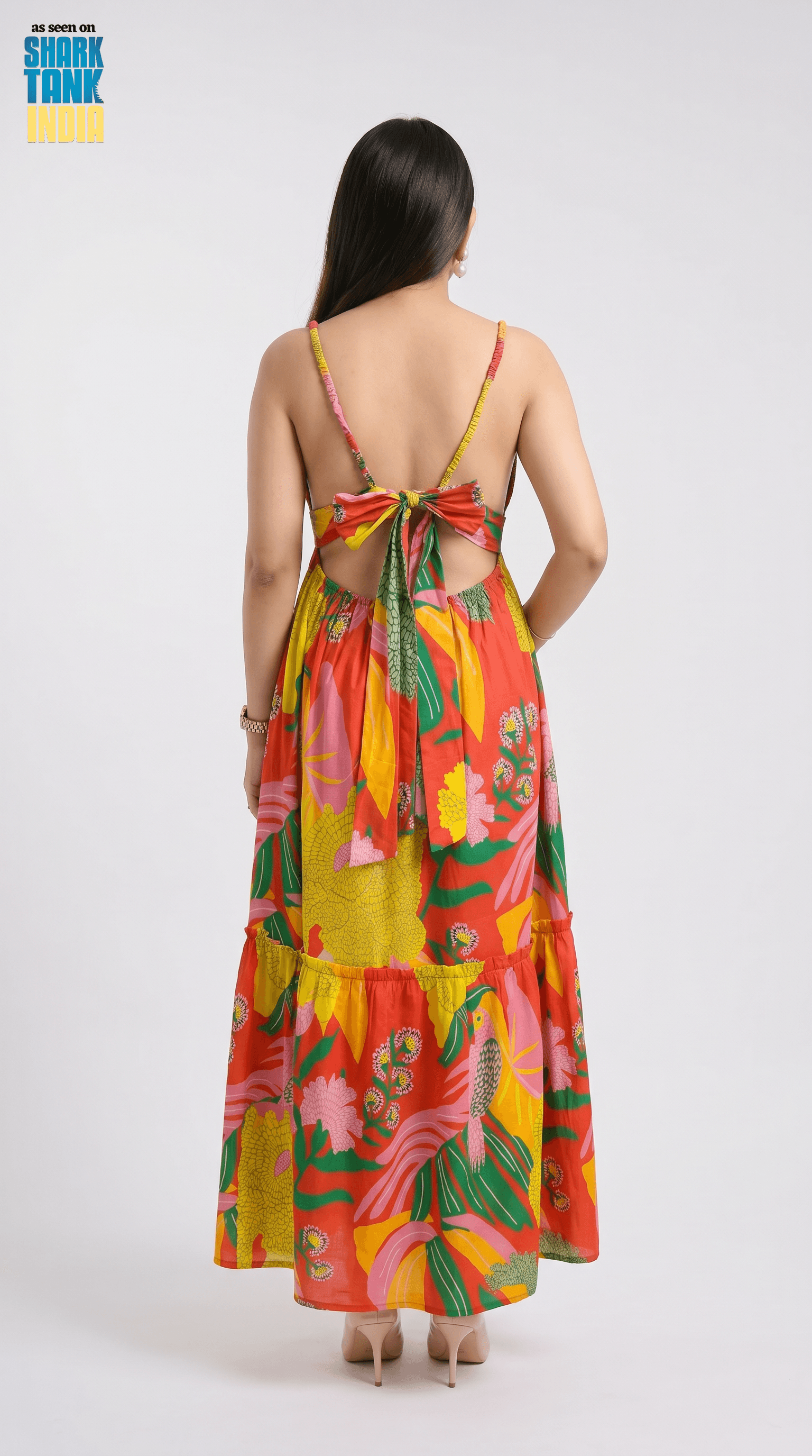 Woman wearing a colorful floral dress with a back bow on a white background