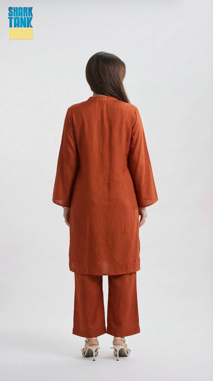 Person wearing a rust-colored outfit on a white background