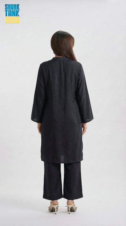 Person wearing a black outfit with wide-leg pants on a white background