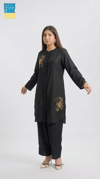 Woman wearing a black outfit with gold embroidery on a white background