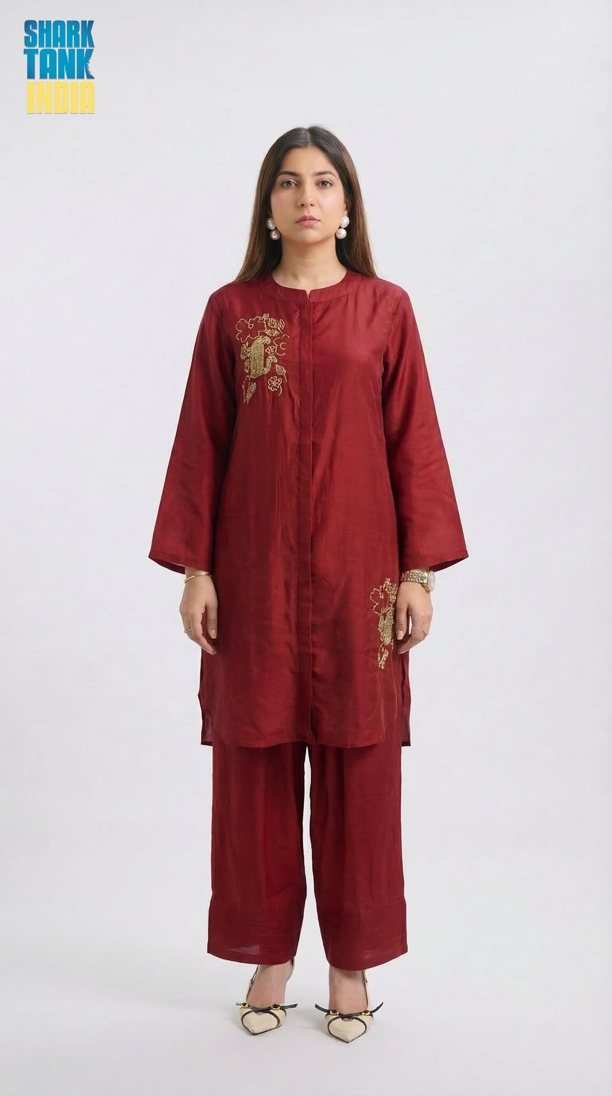 Woman wearing a maroon outfit with gold embroidery on a white background