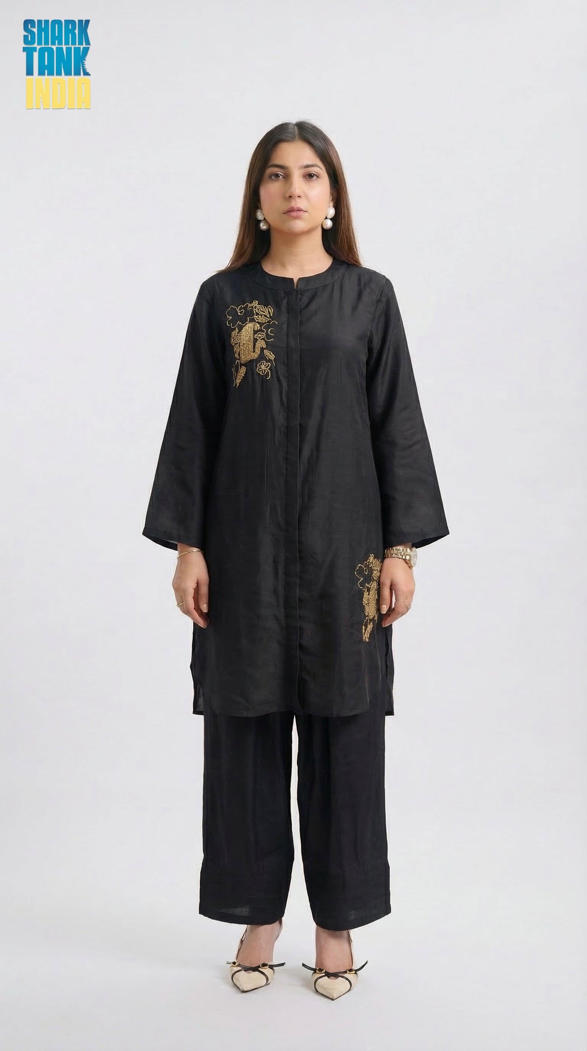 Woman wearing a black outfit with gold embroidery on a white background