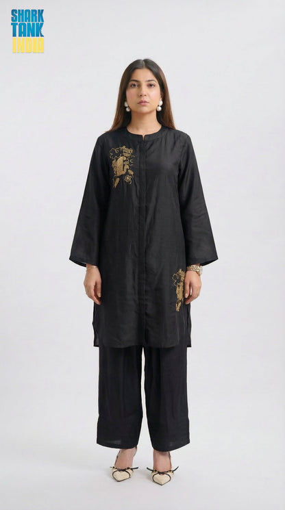 Woman wearing a black outfit with gold embroidery on a white background