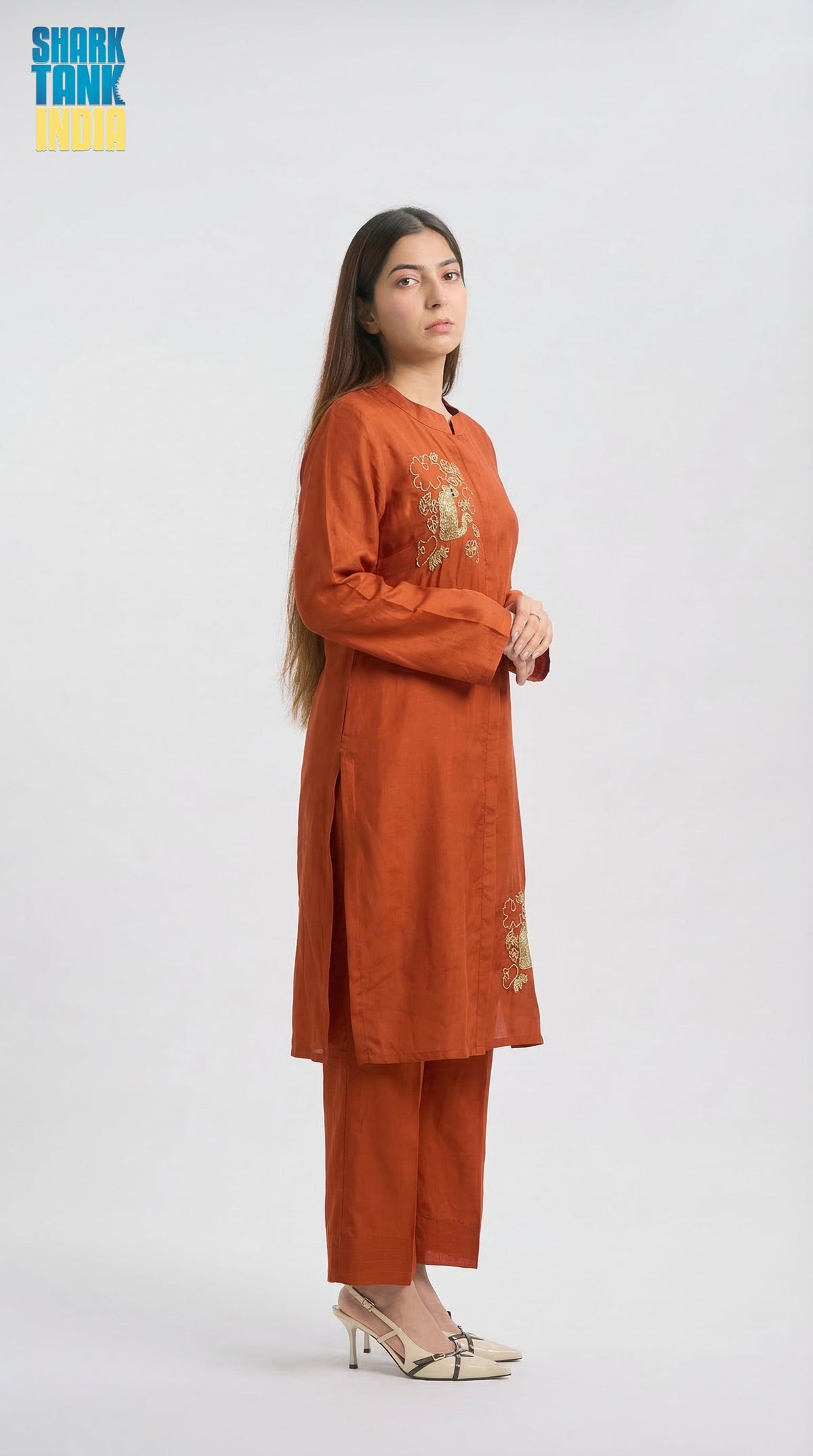 Woman wearing an orange outfit with embroidery on a white background