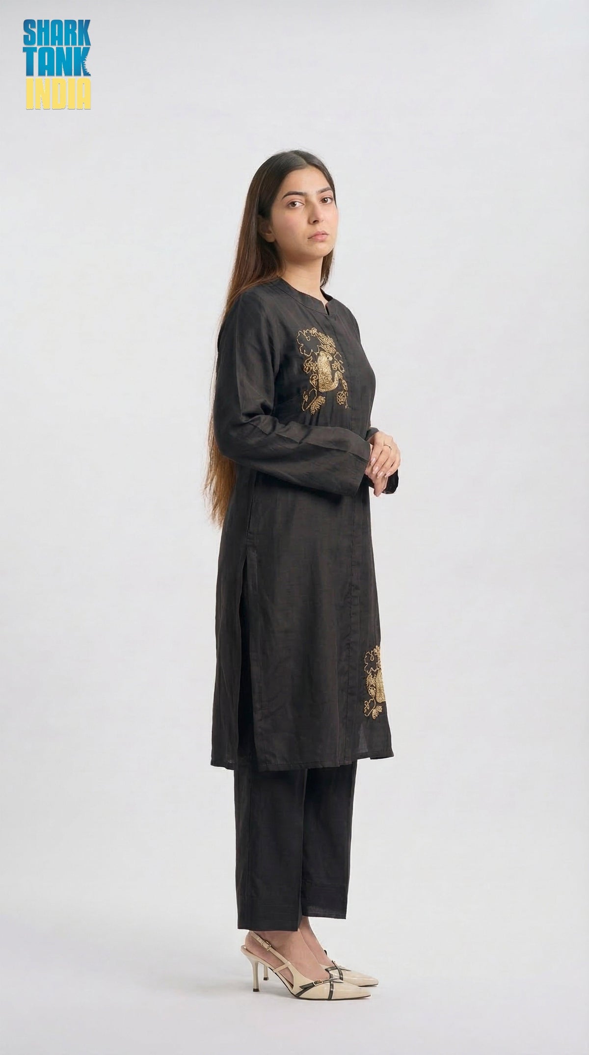 Woman wearing a black outfit with gold embroidery on a white background