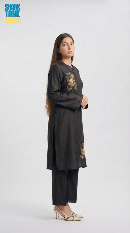 Woman wearing a black outfit with gold embroidery on a white background
