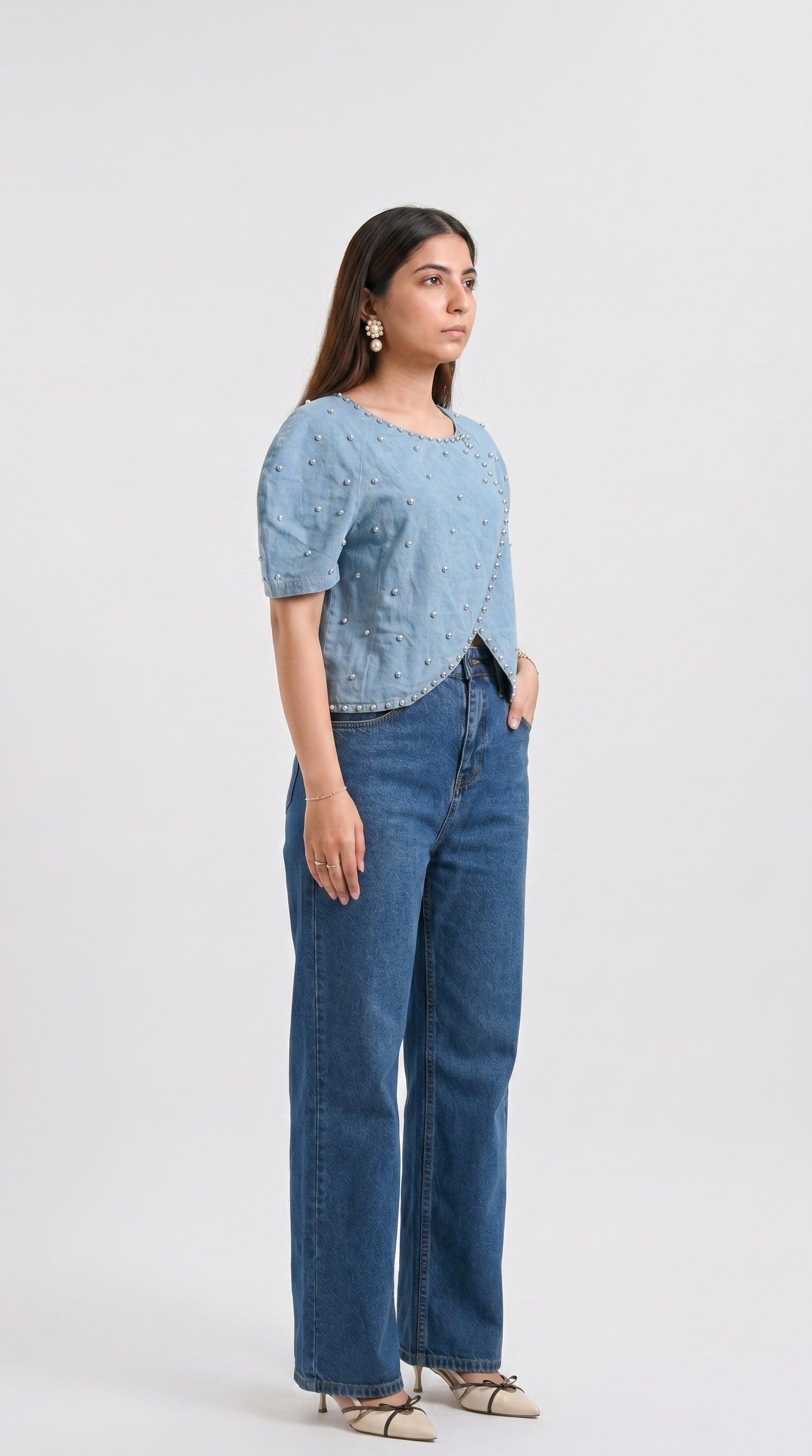 Woman wearing a light blue top and dark blue jeans on a white background
