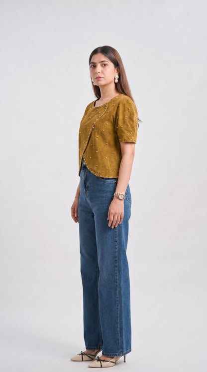 Woman wearing a mustard yellow top and blue jeans on a white background