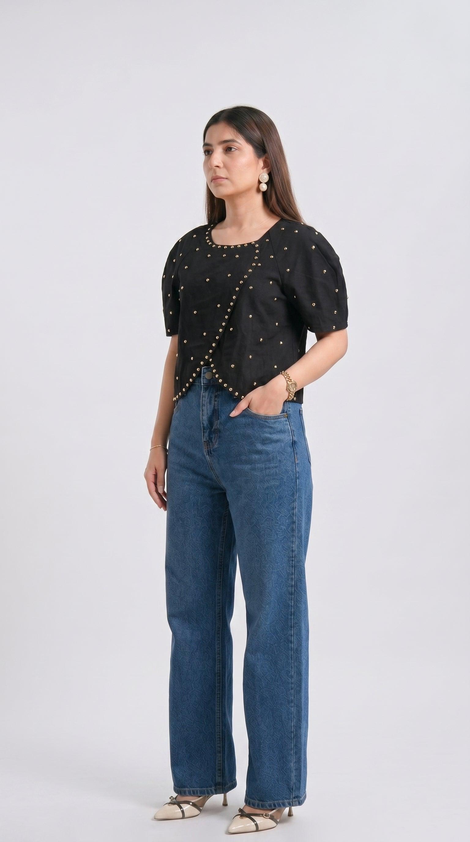 Woman wearing a black top with star patterns and blue jeans on a white background