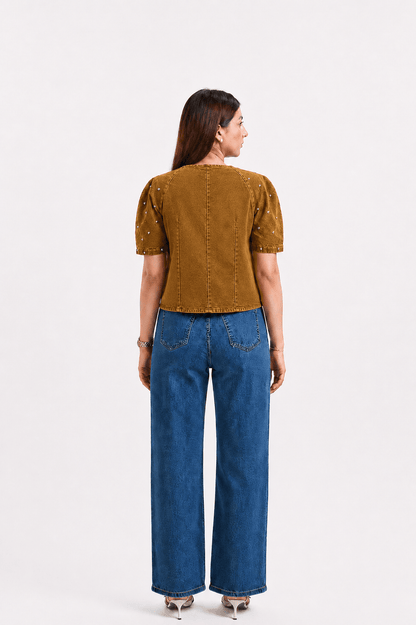 Woman wearing a mustard yellow top and blue jeans on a white background