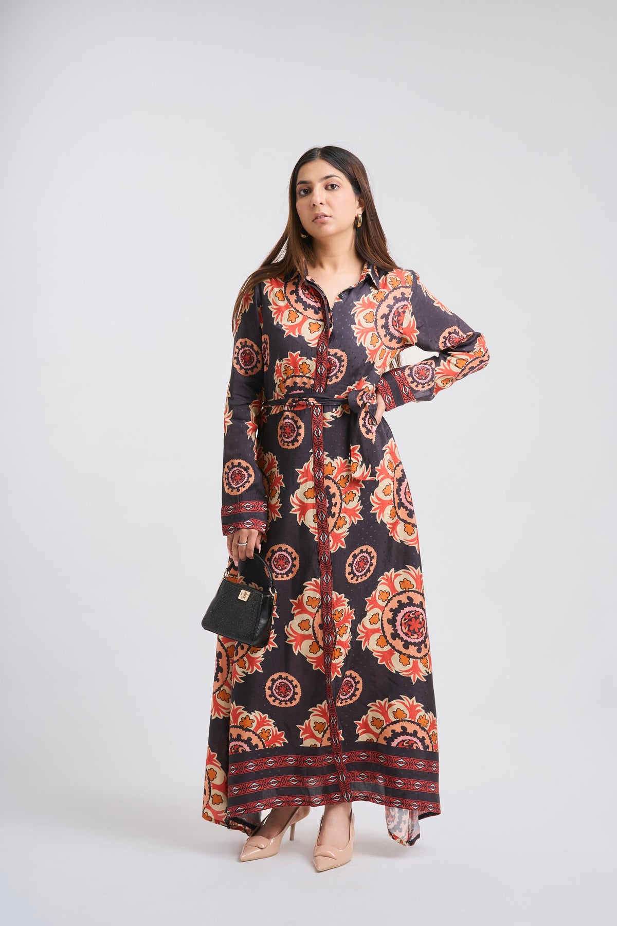 Woman wearing a long, patterned dress against a white background