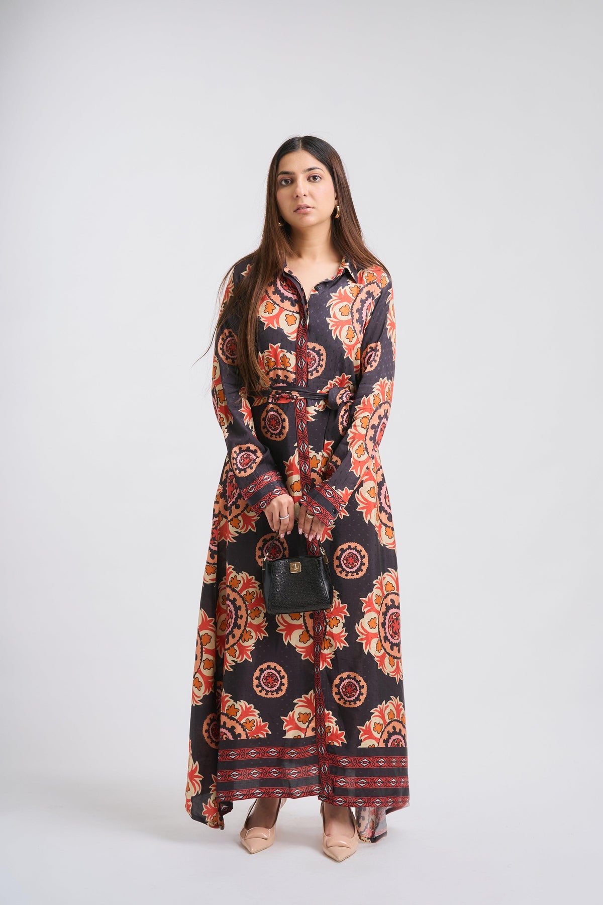Woman wearing a long, patterned dress on a white background