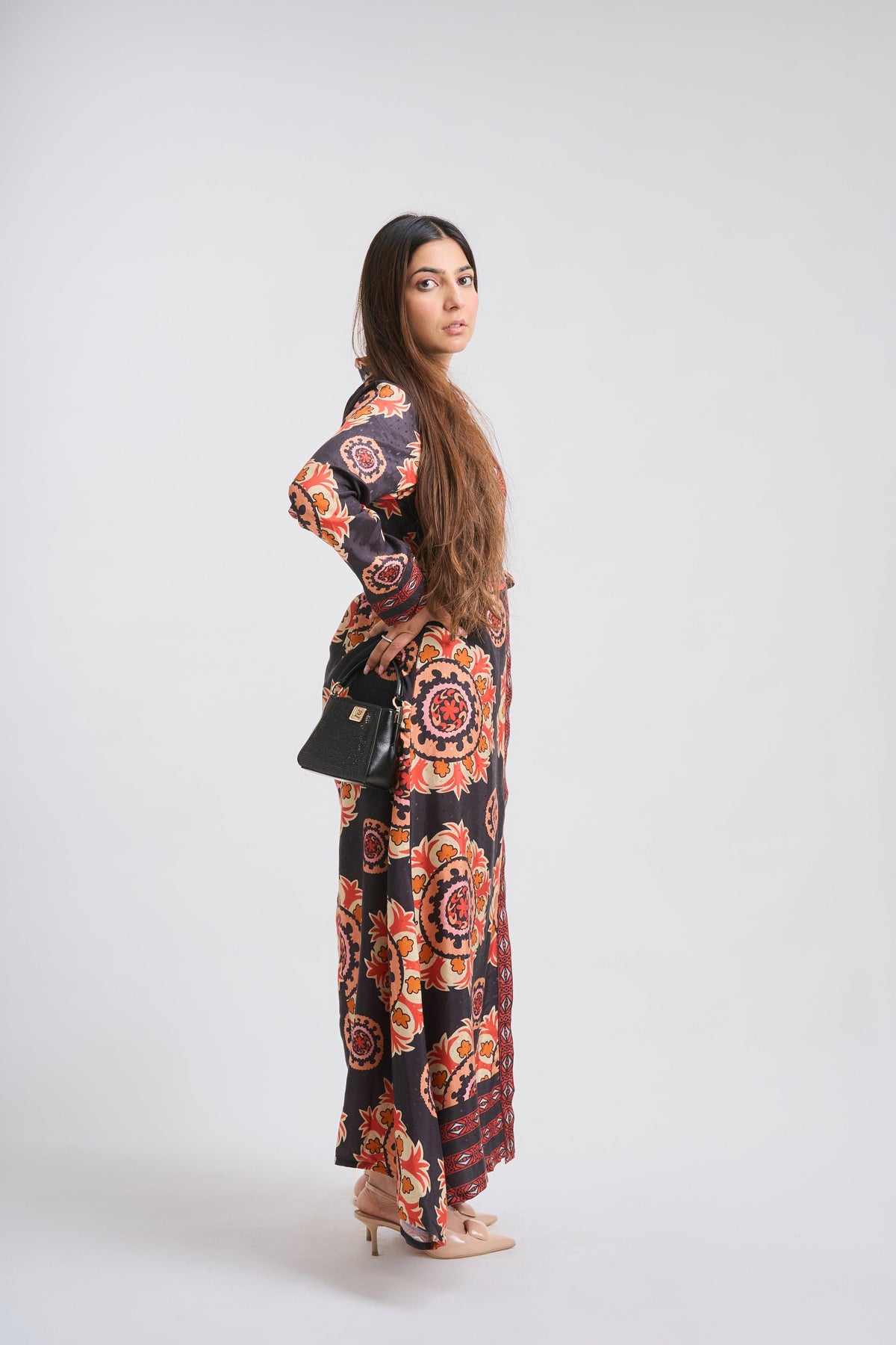 Woman wearing a long, patterned dress on a white background