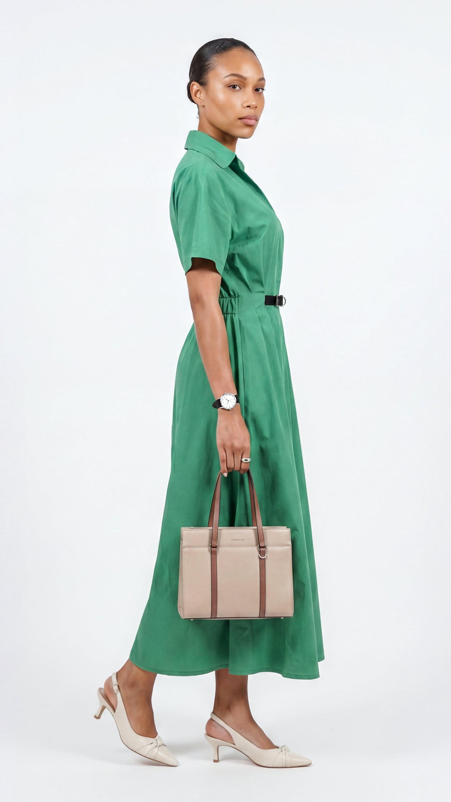 Woman in a green dress holding a beige handbag on a white background