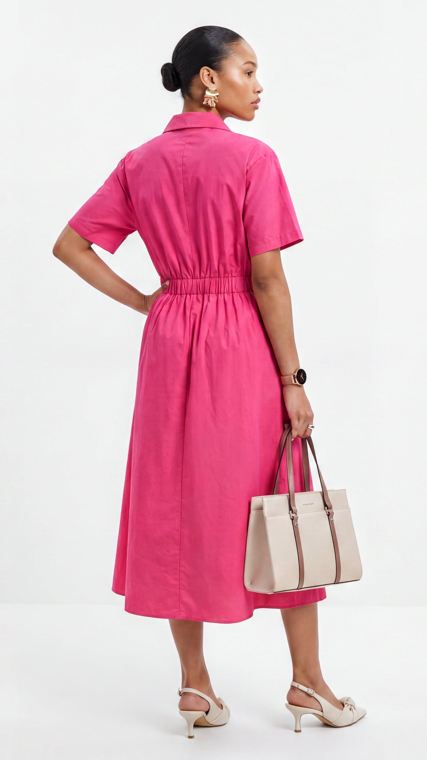 Woman wearing a pink dress holding a beige handbag on a white background