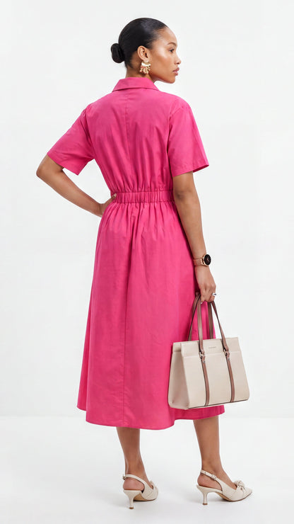 Woman wearing a pink dress holding a beige handbag on a white background