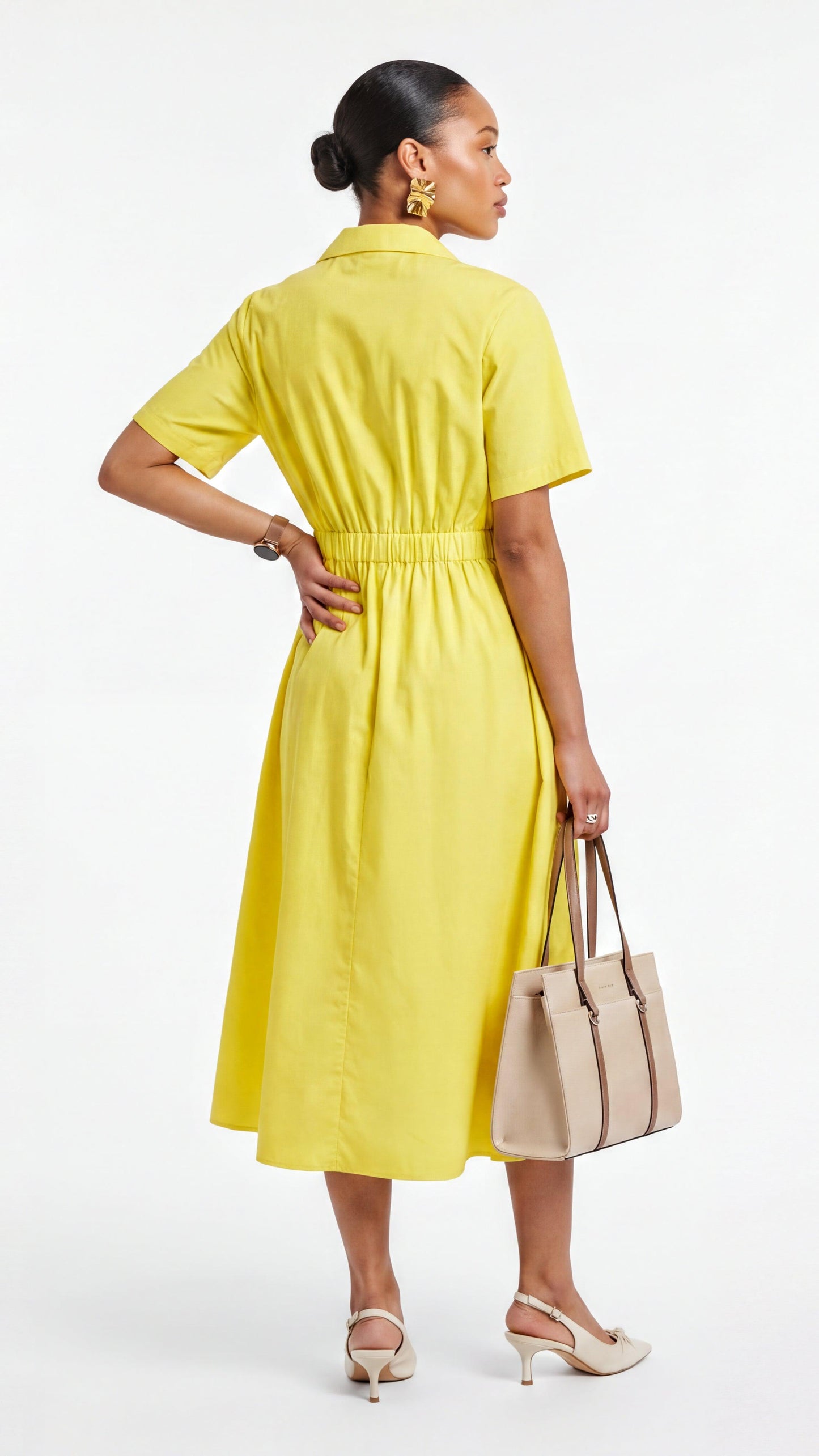 Woman wearing a yellow dress holding a beige handbag on a white background
