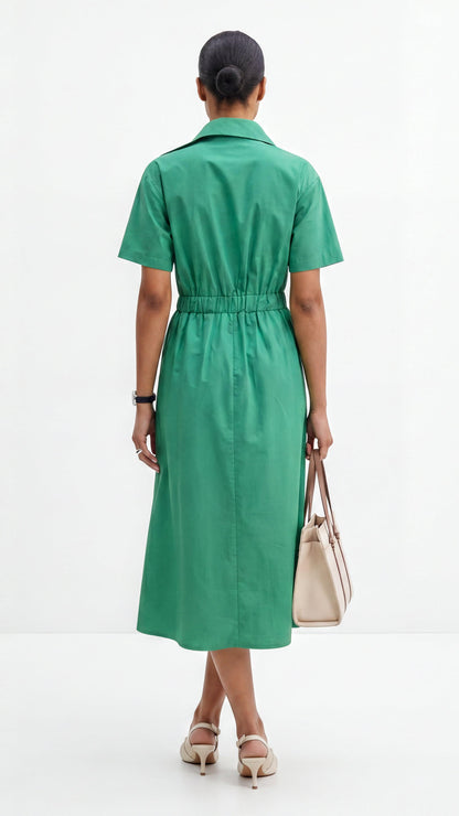 Woman wearing a green dress holding a beige handbag on a white background