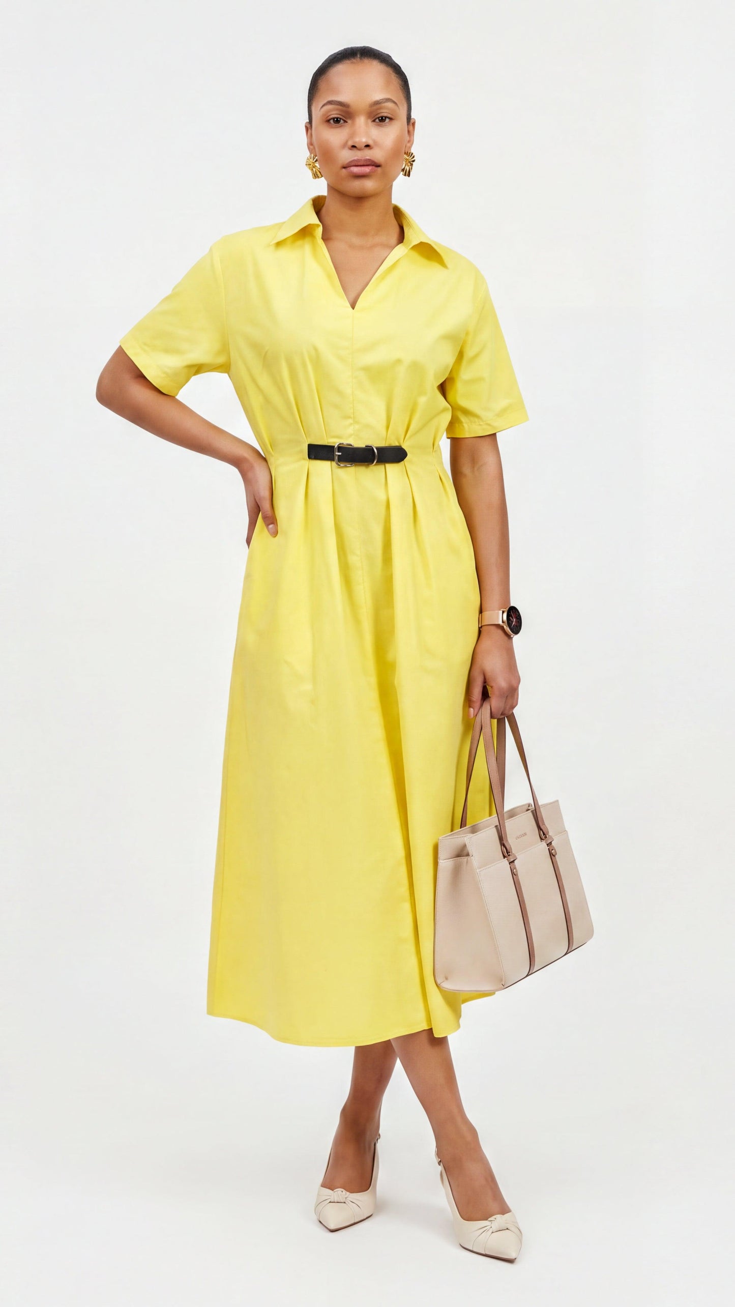 Woman wearing a yellow dress holding a beige handbag on a white background