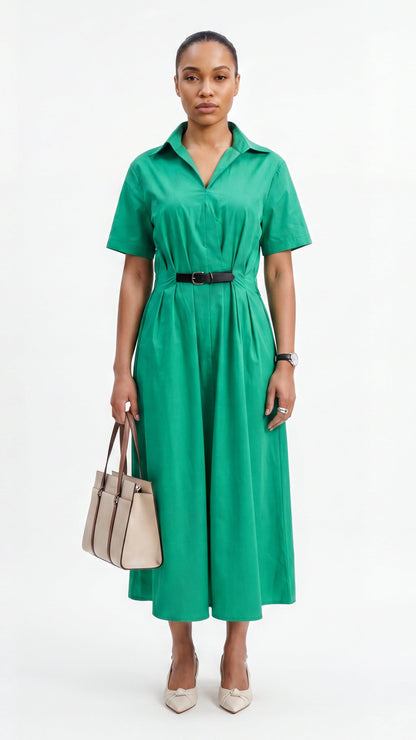 Woman wearing a green dress with a belt, holding a beige handbag on a white background