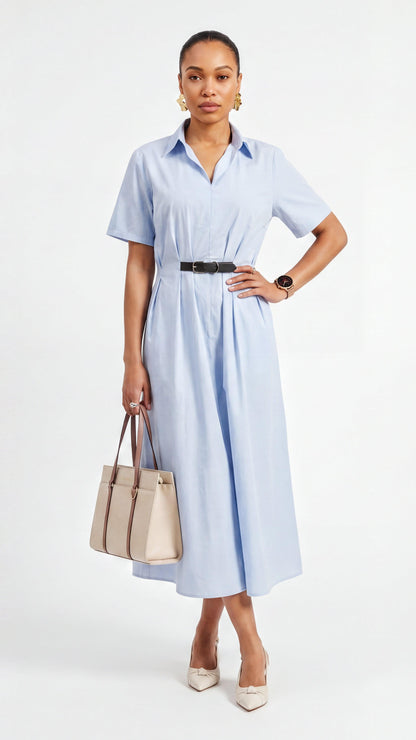 Woman wearing a light blue dress holding a beige handbag on a white background