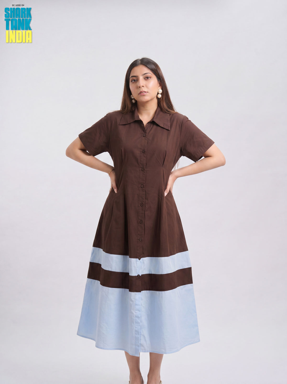 Woman wearing a brown and light blue dress with 'Shok Tank India' logo in the corner.