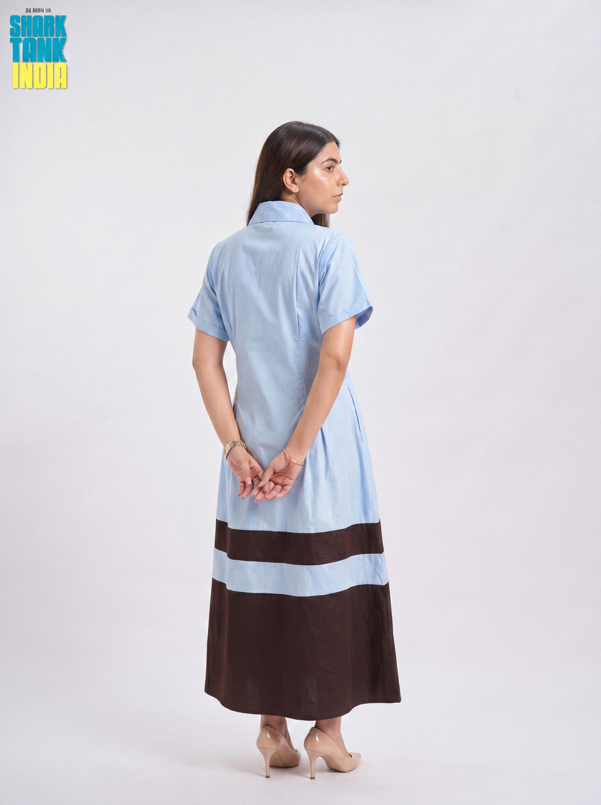 Woman wearing a light blue and brown dress on a white background