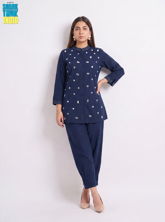 Woman wearing a navy blue traditional outfit with white patterns on a white background