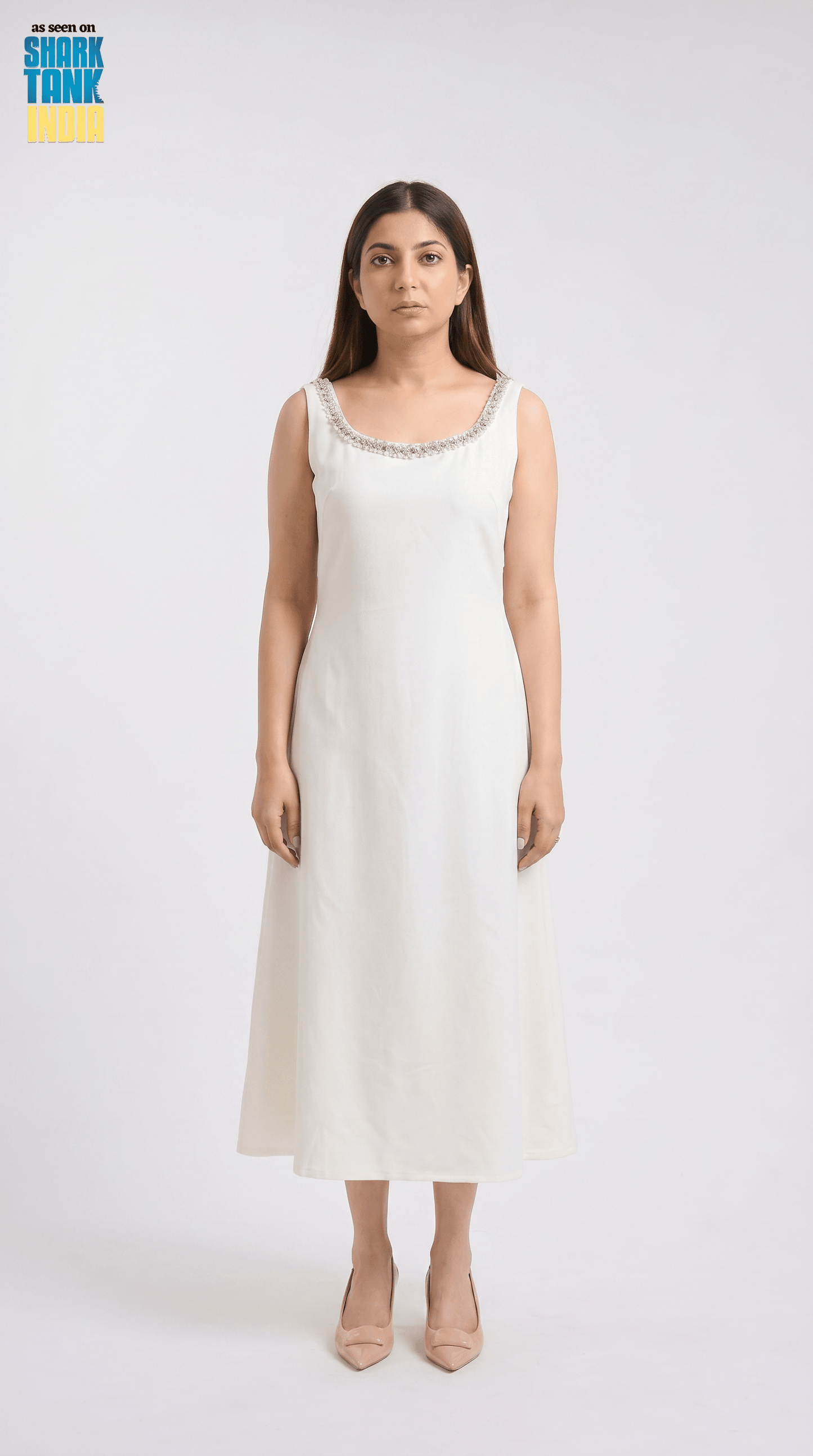 Woman wearing a white sleeveless dress with a subtle pattern on a white background