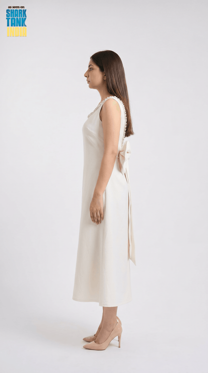 Woman wearing a white sleeveless dress with a bow detail on a white background